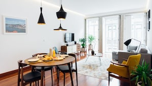 Ein modernes Wohnzimmer mit Essbereich, ausgestattet mit einem runden Tisch, Stühlen, einer Couch und einem Fernseher.