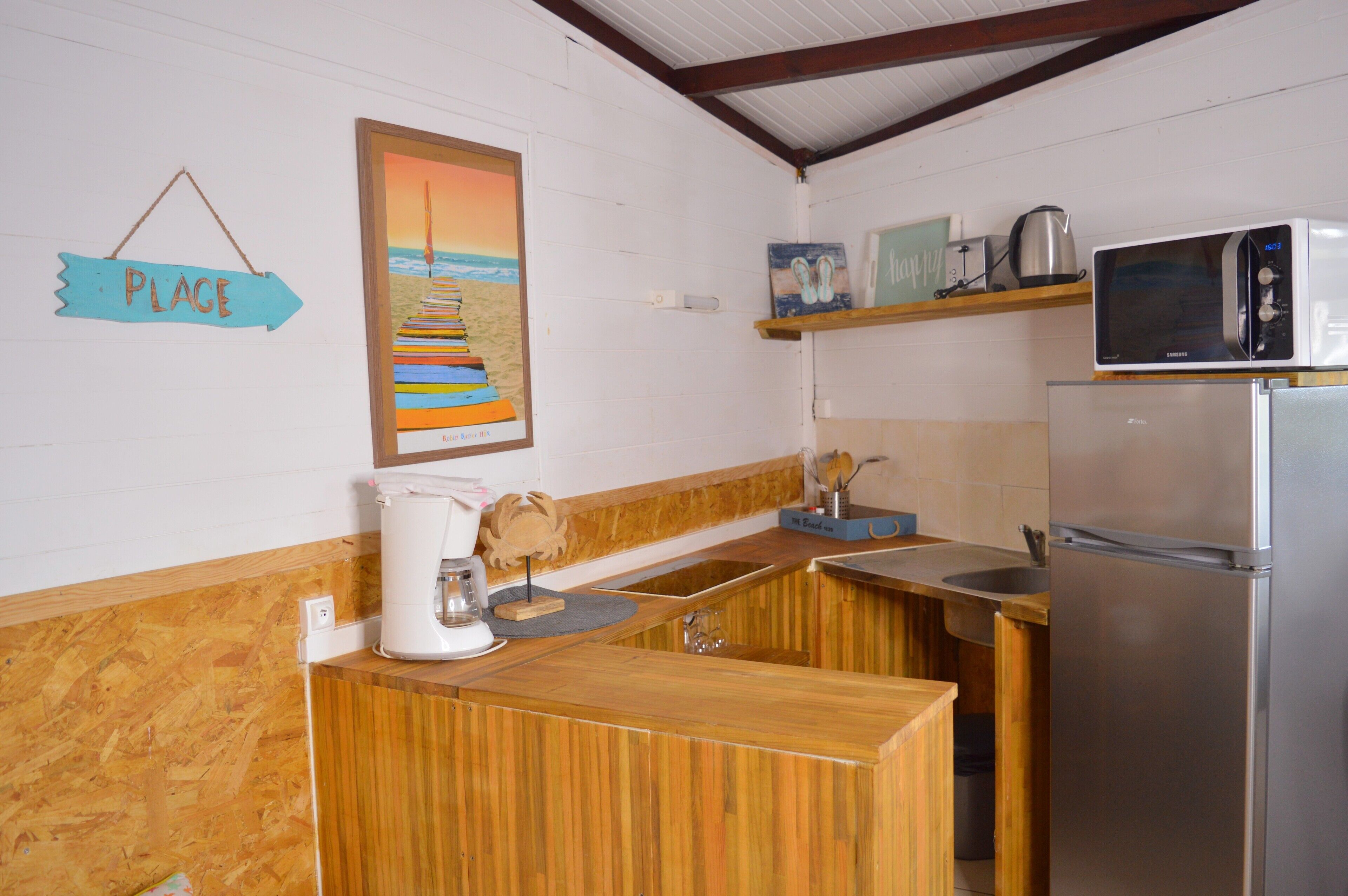 A kitchen with wooden cabinets, a stainless steel refrigerator, a microwave, and a coffee maker.
