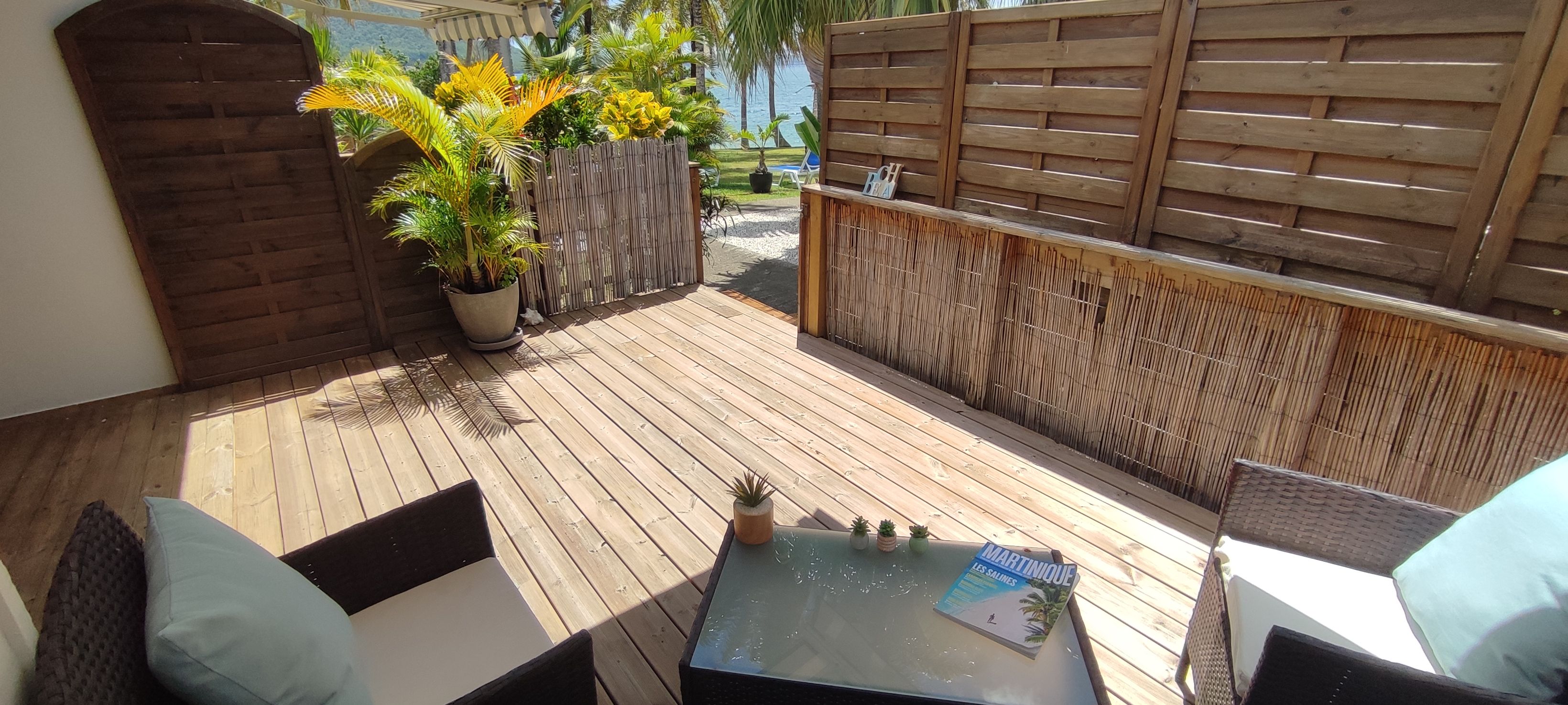 A wooden deck with outdoor furniture, a potted plant, and a magazine on a table.