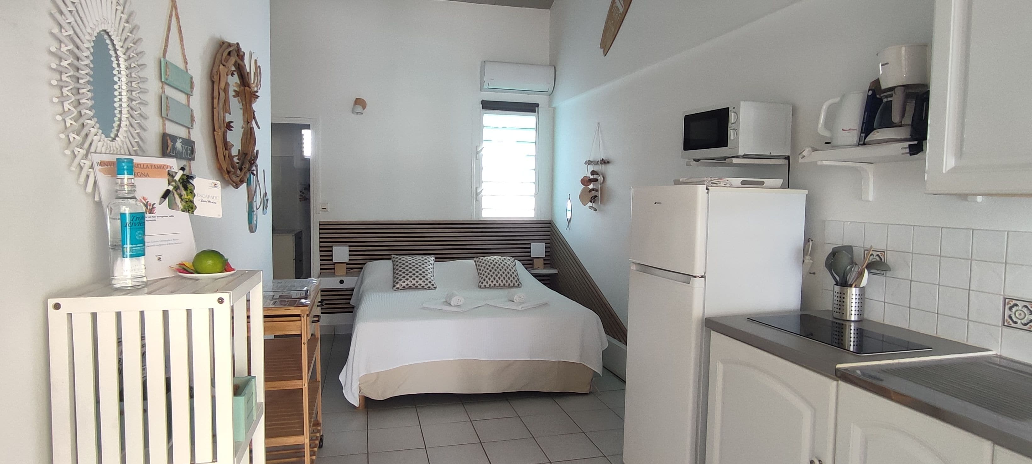 Une chambre d’hôtel de taille réduite, comprenant un lit, une petite kitchenette et une salle de bain.