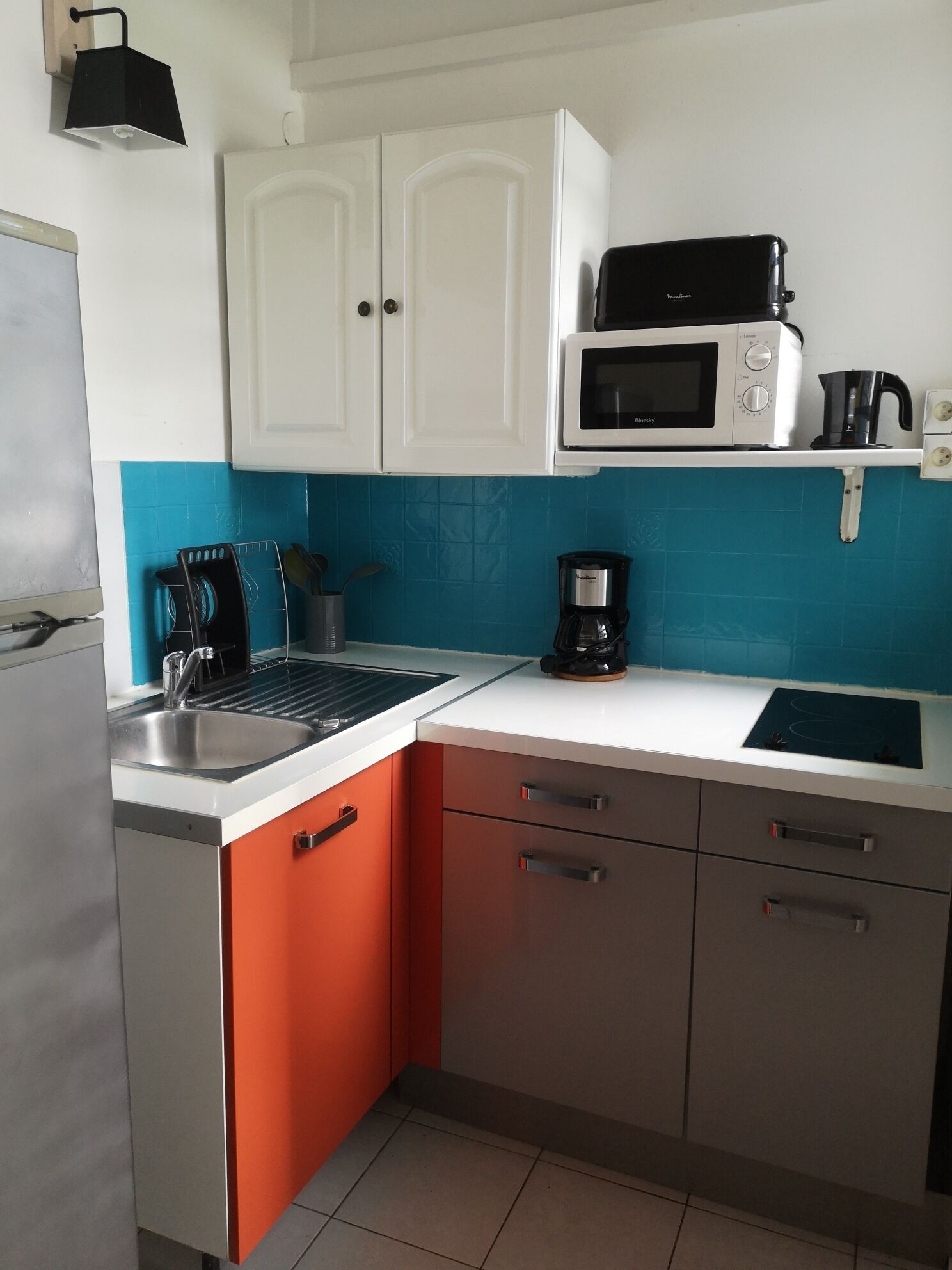 A kitchen with white cabinets, a microwave, a coffee maker, and a sink.