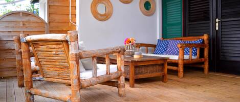 A wooden deck with a rustic bench and a small table, a wicker basket, and a wall with three circular mirrors.