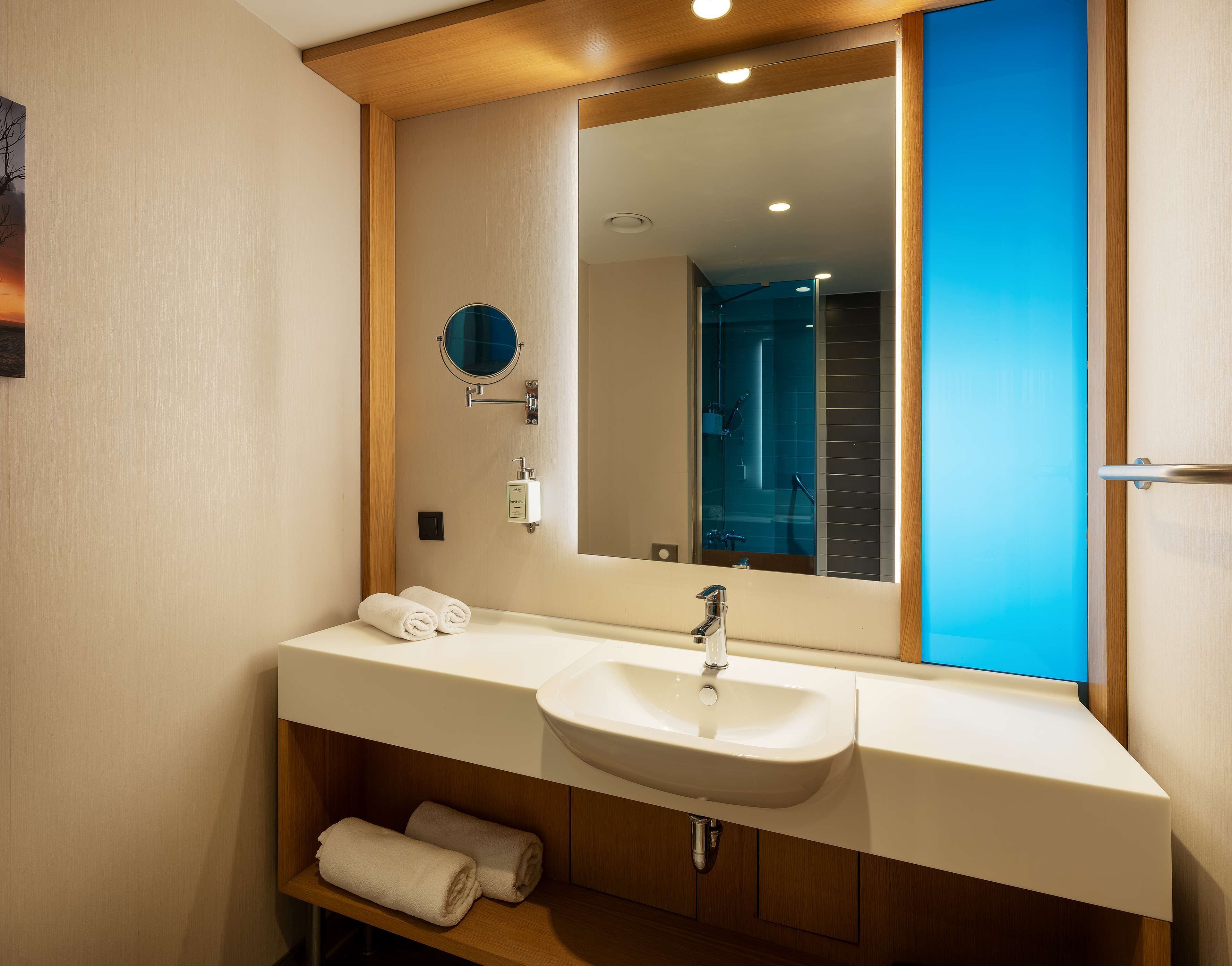 A modern bathroom with a double sink, a large mirror, and a towel rack.