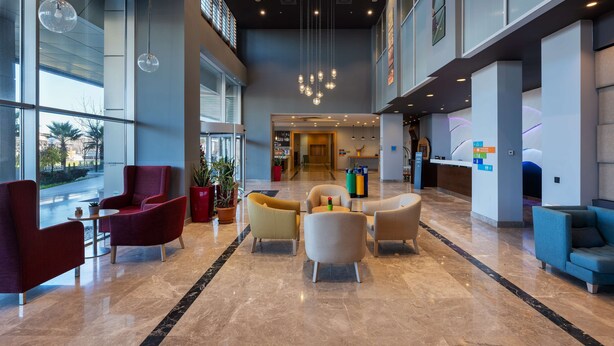 A spacious lobby with modern seating, a reception desk, and a view of the outdoors. - Park Inn by Radisson Samsun (Tekkekoy)