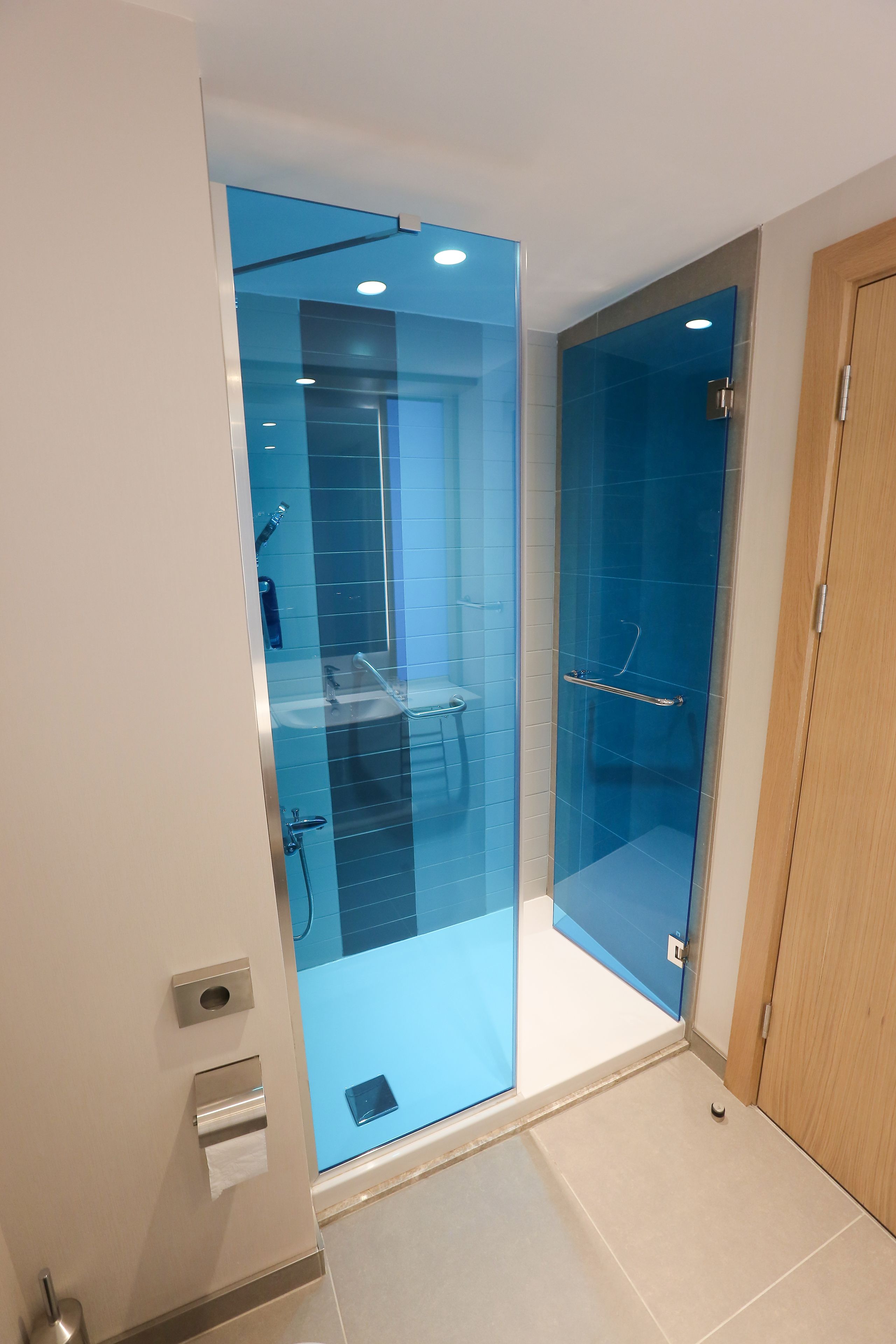 Un bagno moderno con porte doccia in vetro, porta carta igienica e porta in legno.