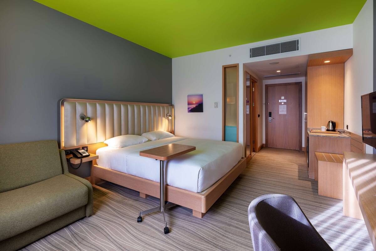 A hotel room with a bed, a desk, a chair, and a sofa.