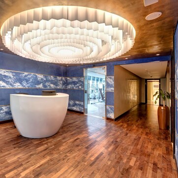 A modern reception area with a circular light fixture, marble walls, and a wooden floor.
