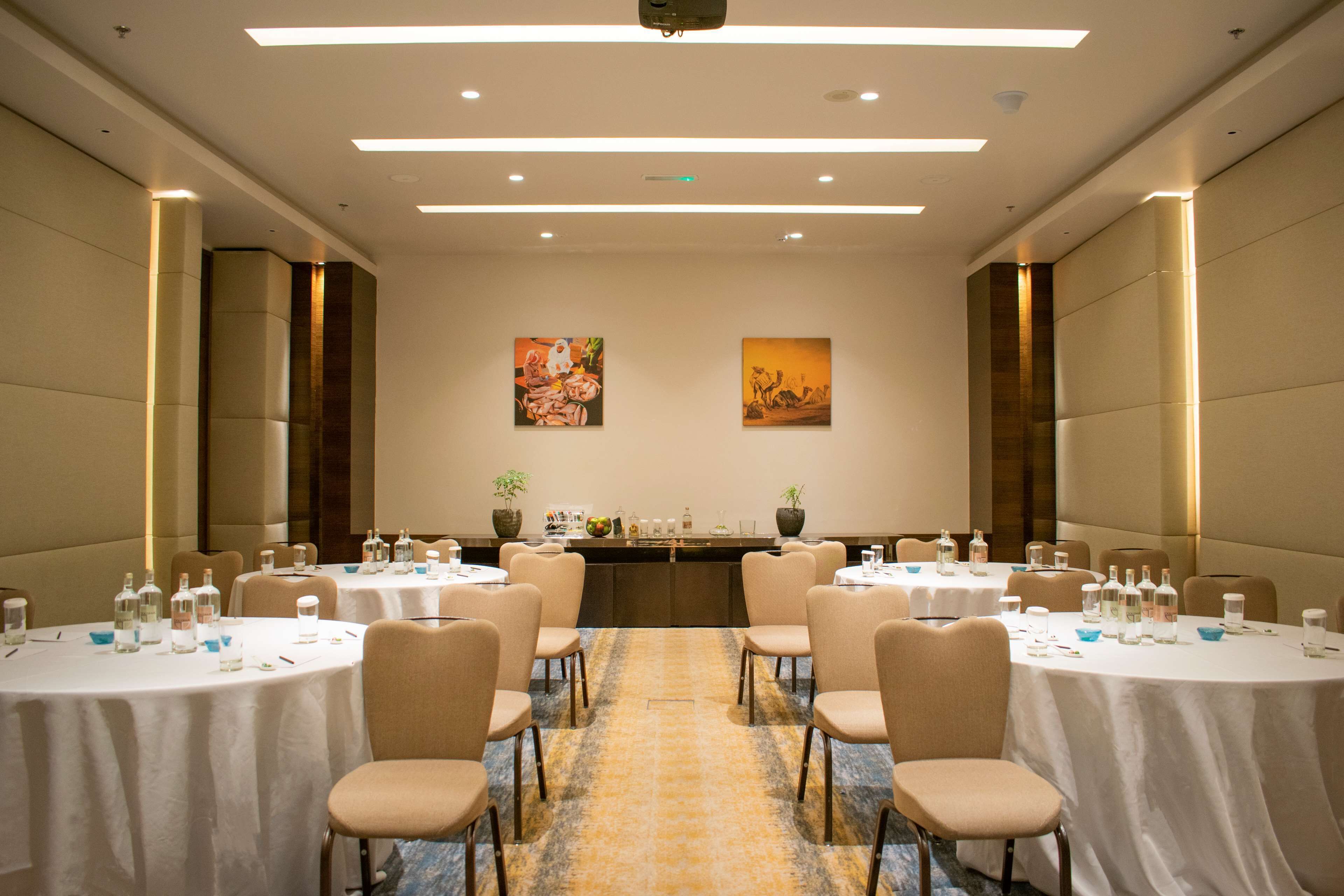 A conference room with round tables, chairs, and a carpeted floor.