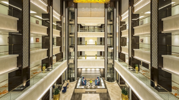 Een meerlaags atrium met glazen balustrades, een centrale trap en decoratieve verlichting.
