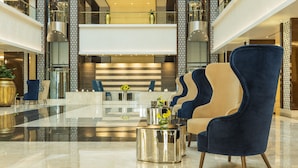 Een moderne lobby met een receptiebalie, zithoek en decoratieve elementen.