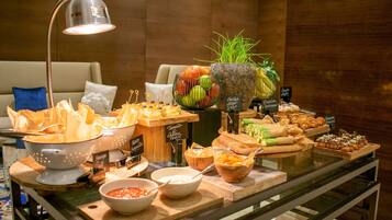 A buffet table with various food items and a potted plant.