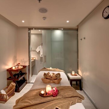 A modern spa room with a massage table, candles, and a serene atmosphere.