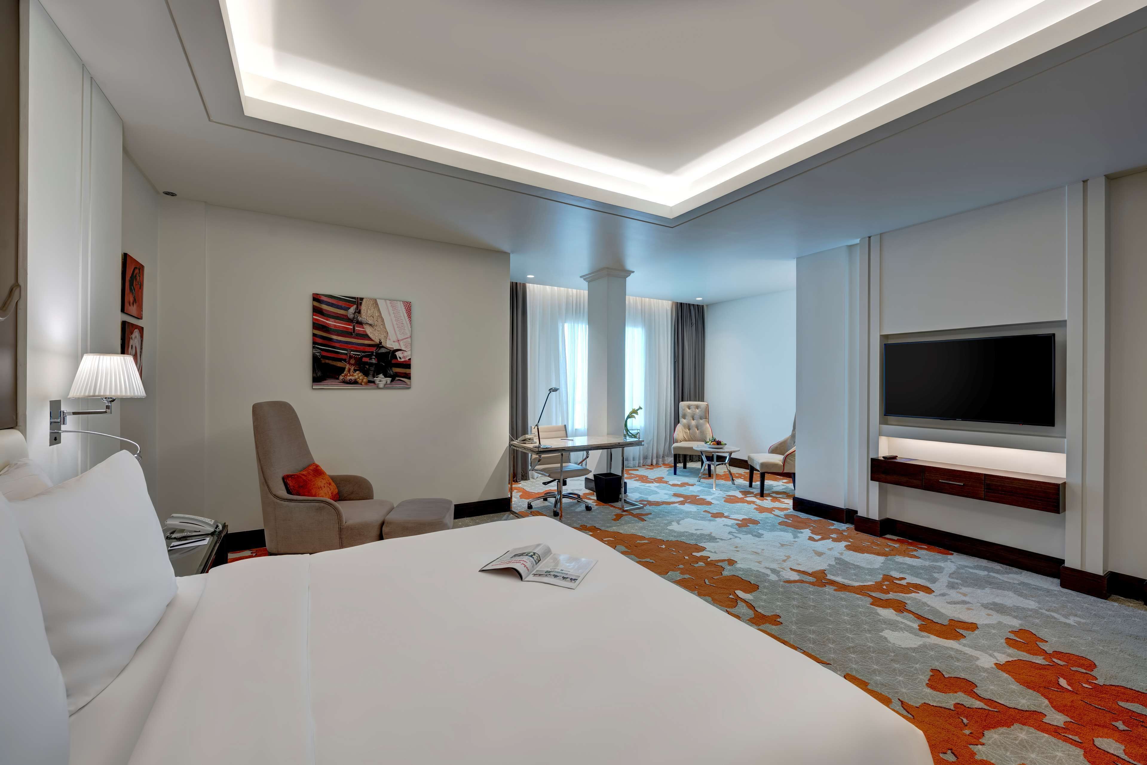 Une chambre d’hôtel avec un grand lit, un bureau, une télévision et une vue sur la ville.