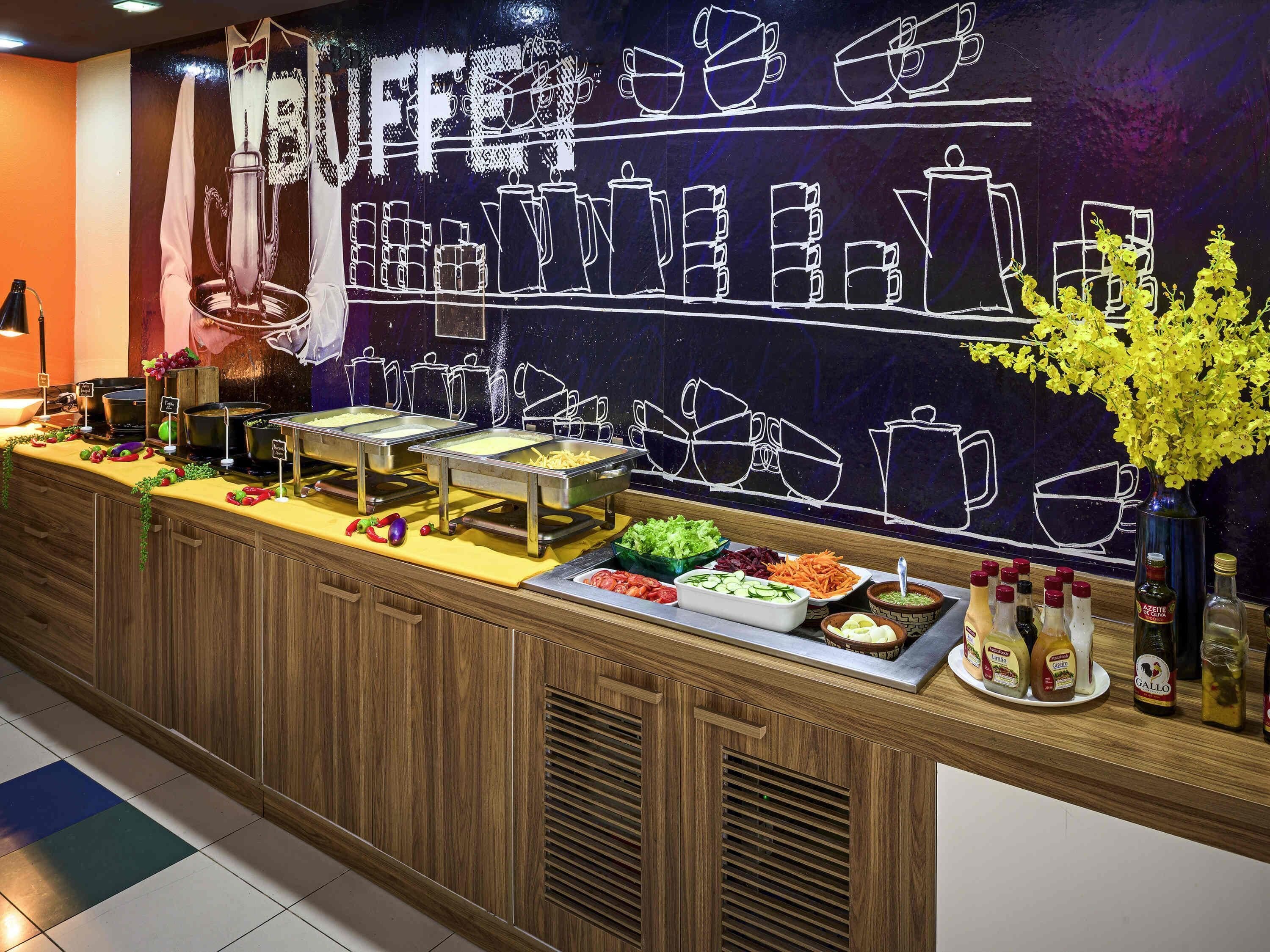 A buffet counter with various food items and condiments.
