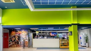 Un área de recepción de colores vivos con un mostrador, una pantalla de televisión y una exhibición de alimentos.