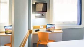 Una habitación pequeña con una cama, un escritorio con una computadora portátil y una silla.