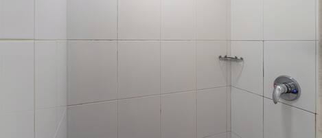 A small, tiled shower room with a ceiling light and a showerhead.