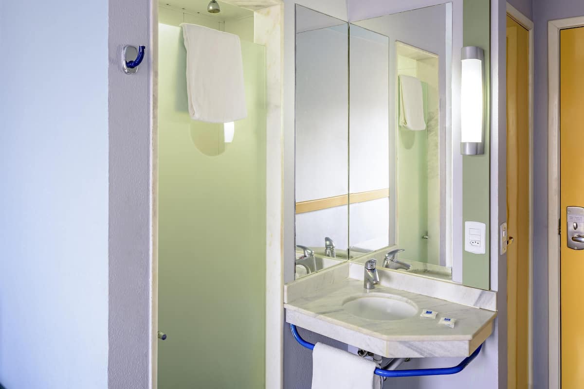 A bathroom with a sink, mirror, and towel hanging on the wall.