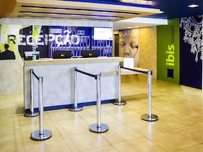 A reception area with a counter, a large poster, and a sign for 'ibis budget'. - ibis budget Sertaozinho (Sertaozinho)