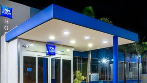 A hotel entrance with a blue canopy, glass doors, and a sign for ibis budget hotels. - ibis budget Sertaozinho (Sertaozinho)