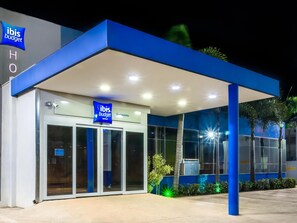 A hotel entrance with a blue canopy, glass doors, and a sign for ibis budget hotels. - ibis budget Sertaozinho (Sertaozinho)