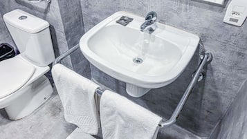 A bathroom with a white toilet, a sink with a mirror above it, and a towel rack with two towels.