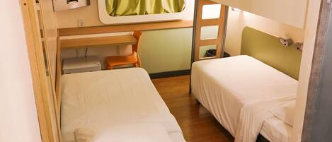 A compact hotel room with bunk beds, a small desk, a chair, and a television.