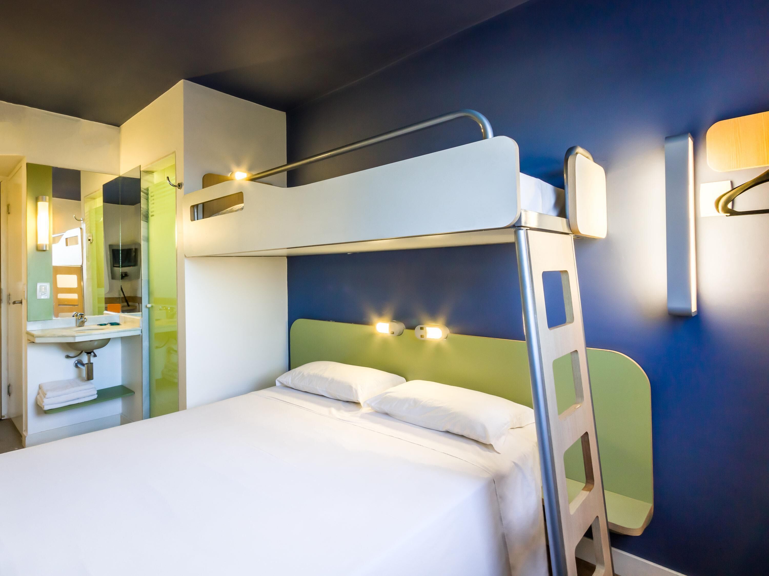 A bunk bed with a headboard, a bedside table, and a mirror.