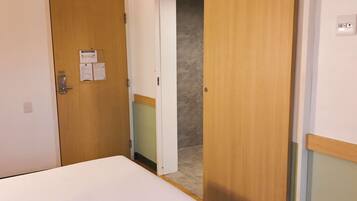 A hotel room with a bed, a wooden door, and a small closet.