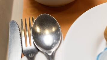 A white bowl of scrambled eggs on a beige tray with a fork and spoon beside it.