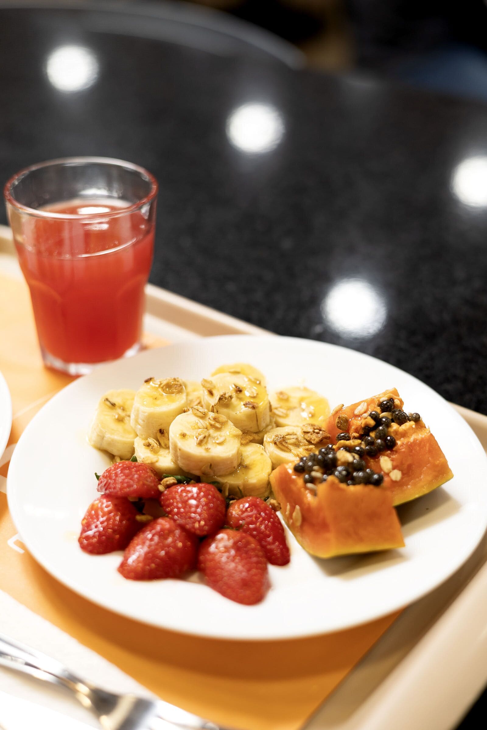 A plate with sliced bananas, strawberries, and a piece of bread with seeds.