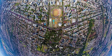 Vista aérea de una zona urbana densamente poblada con un complejo deportivo central, rodeado de edificios residenciales y calles estrechas.