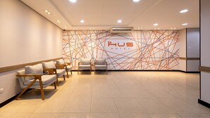 Ein Hotel-Empfangsbereich mit modernem Design, der sich durch ein geometrisches Wandmuster und eine Sitzecke mit Holzbeschilderung auszeichnet.