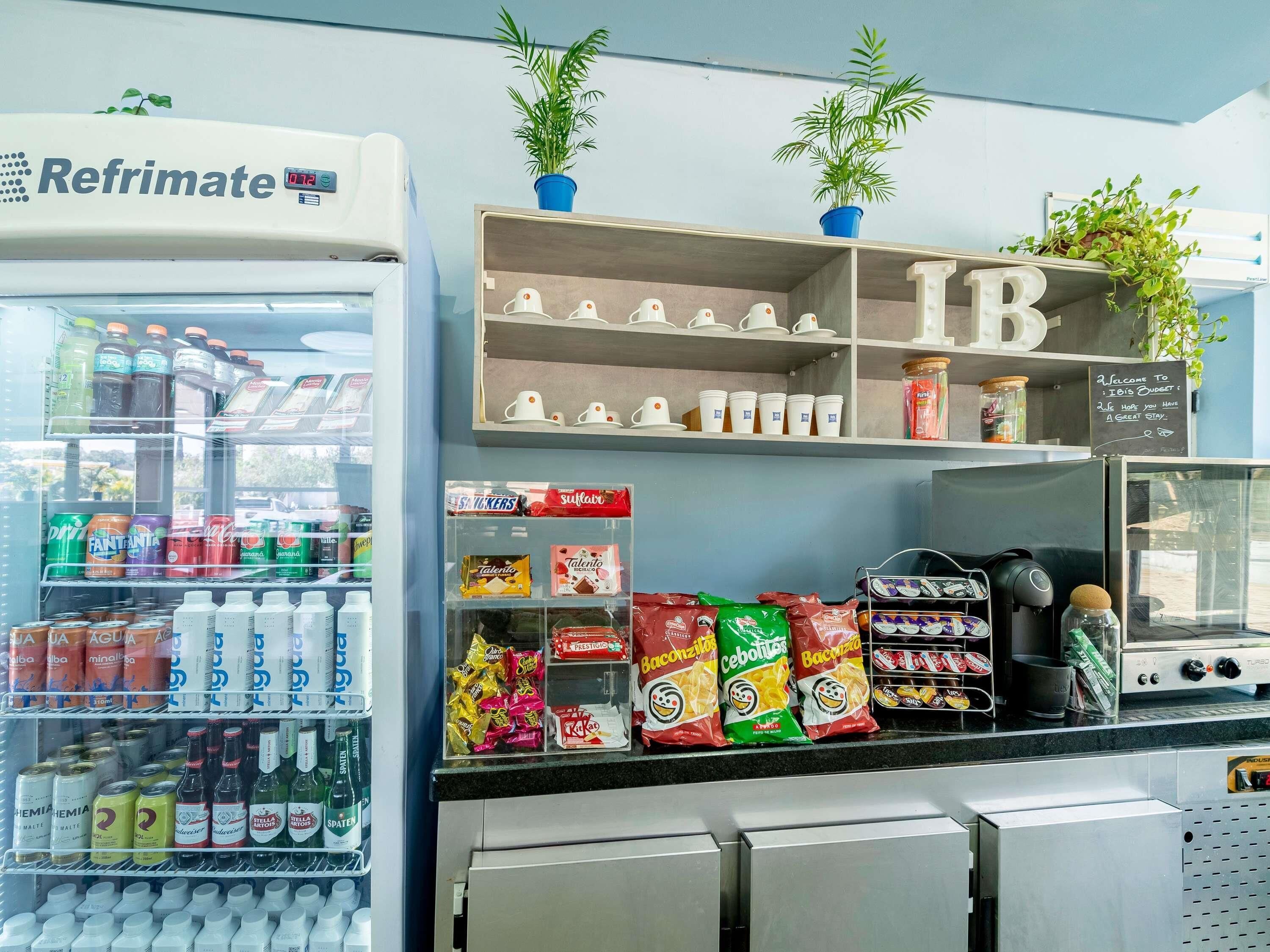 A beverage dispenser, shelves with cups, and snack bags.