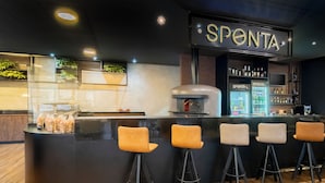 A bar area with a 'SPONTA' sign, a bar counter, stools, and a display of bottled beverages. - ibis budget Piracicaba (Piracicaba)