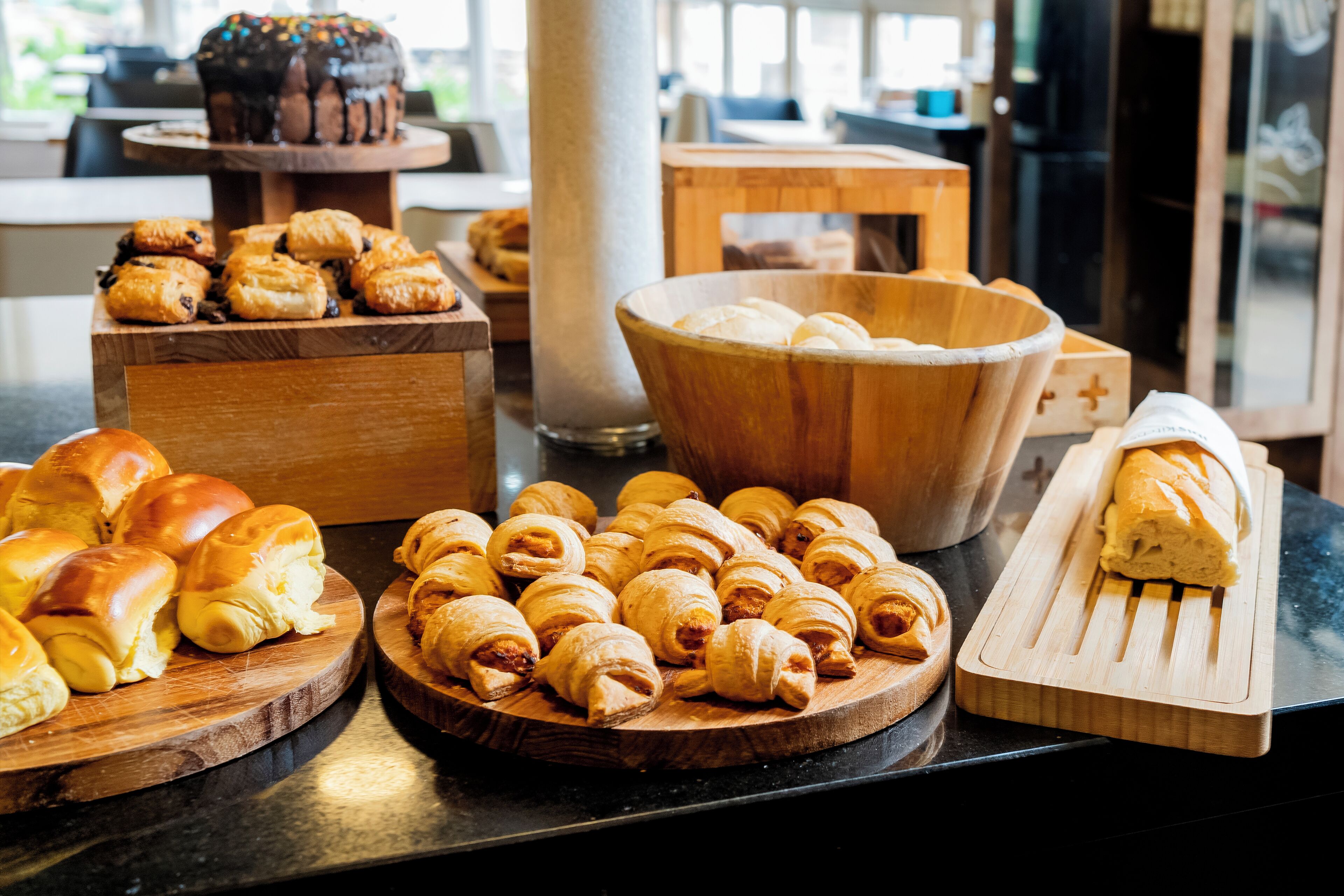 Verschiedene Backwaren auf Holzbrettern, darunter Croissants und ein Brotlaib.