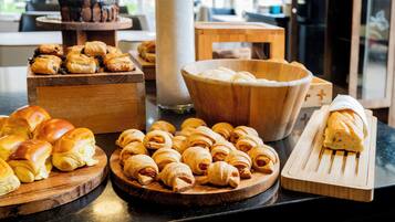 Verschiedene Backwaren auf Holzbrettern, darunter Croissants und ein Brotlaib.