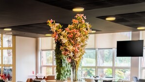 A bakery counter with various baked goods and a floral centerpiece. - ibis budget Piracicaba (Piracicaba)