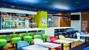 Un caffè moderno con sedute colorate e un bancone che espone diversi prodotti alimentari.
