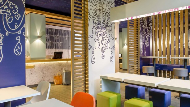 A modern interior with white tables, colorful chairs, and decorative wall art.