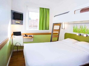 A hotel room with a bed, a desk with a laptop, a TV, and a window with curtains. - ibis budget Campo Grande (Campo Grande)
