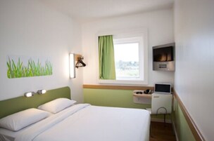 Una habitación de hotel con una cama, un escritorio con computadora, un televisor y una ventana con vista.