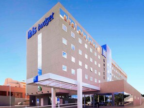 Un hotel moderno con fachada plana, varias ventanas y un llamativo letrero 'ibis budget'.