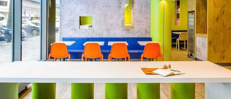 A modern seating area with a white table, blue and orange chairs, and green and yellow accents.