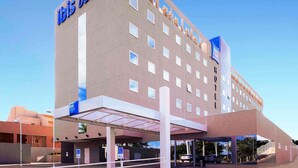 A modern hotel with a flat facade, multiple windows, and a prominent 'ibis budget' sign.