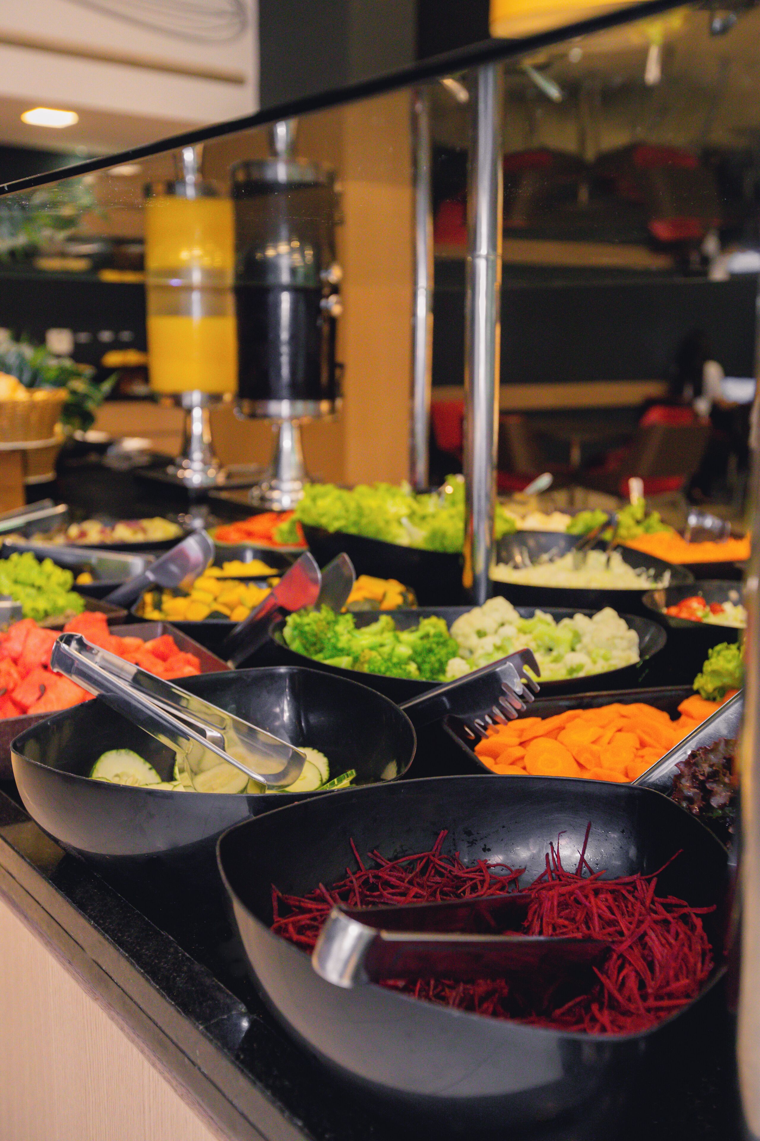 En buffet med et udvalg af mad, herunder grøntsager og frugt.