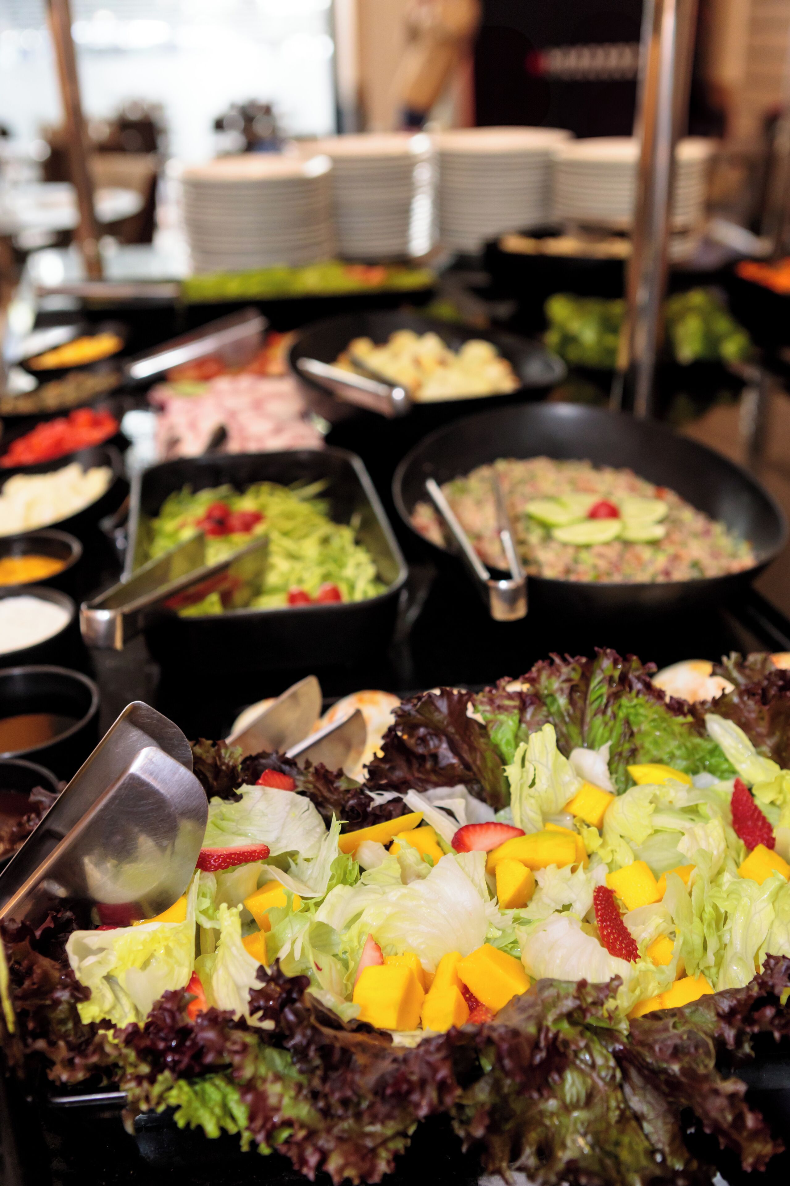 A buffet with various food options including salads, fruits, and meats.