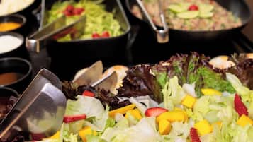 Buffet com diversas opções de comida, incluindo saladas, frutas e carnes.