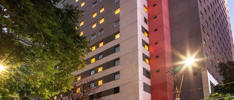A high-rise hotel with multiple floors, a prominent red vertical section, and a well-lit entrance.