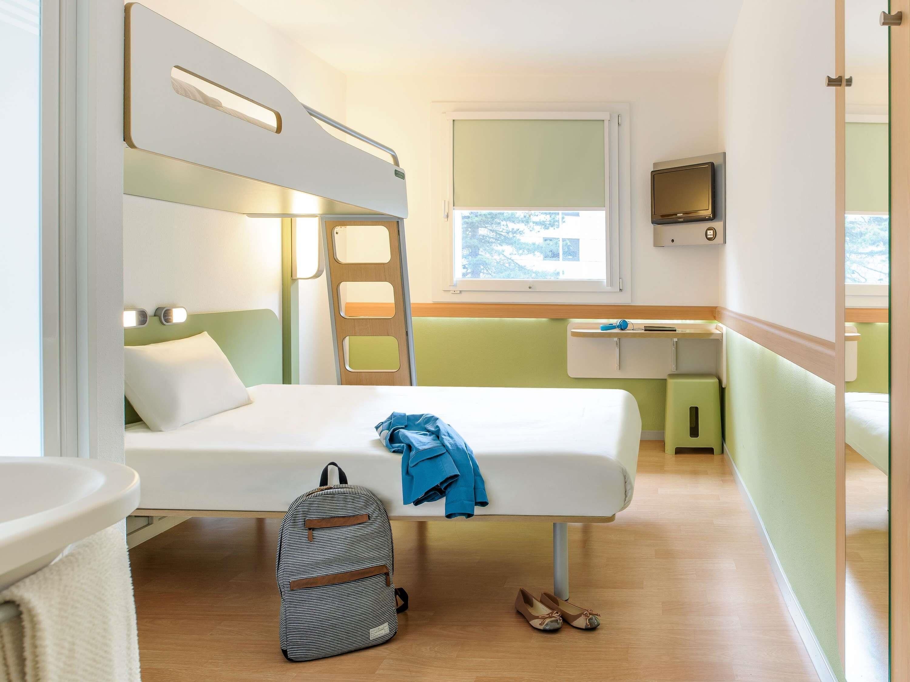 A compact room with bunk beds, a small desk, a TV, and a window with a view.